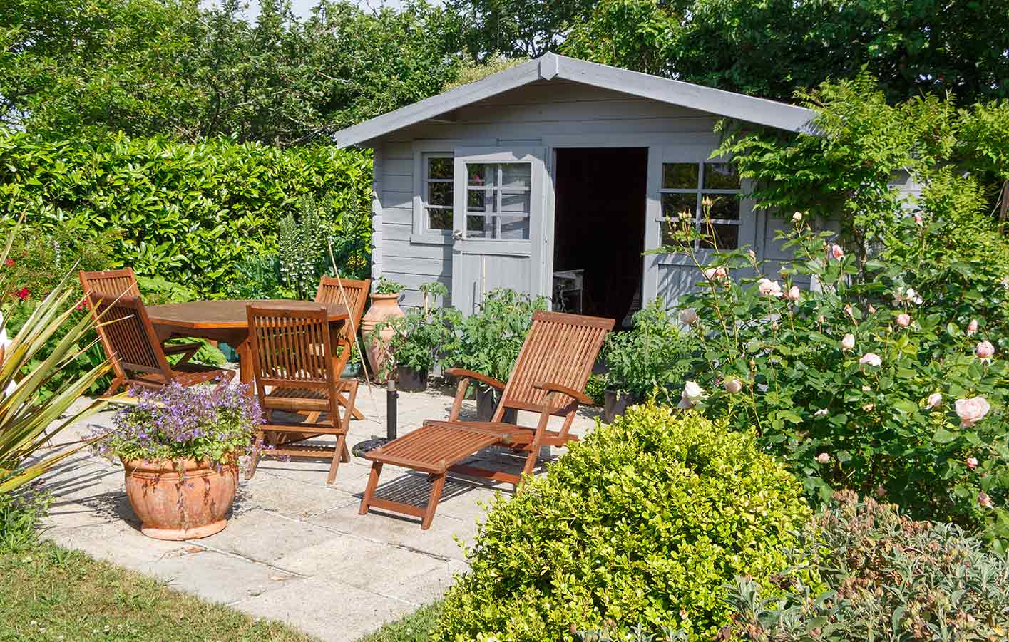 Gartenhaus, davor Gartenstühle und Gartentisch aus Holz